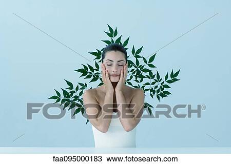 Young woman with hands on cheeks, eyes closed, leafy pattern in background View Large Photo Image Stock Image - Young woman with hands on cheeks, eyes closed, leafy pattern in background. Fotosearch