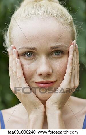 Stock Image - Young woman with hands under chin. Fotosearch
