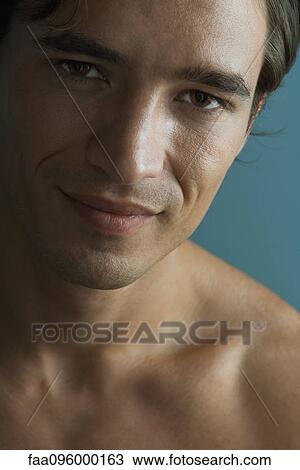 Stock Image - Barechested man looking at camera smiling, close-up. Fotosearch