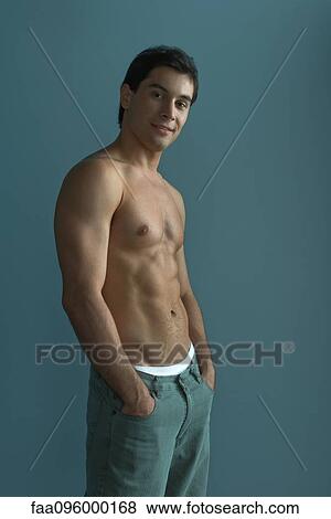 Stock Photo - Barechested muscular man with hands in pockets, smiling at camera. Fotosearch
