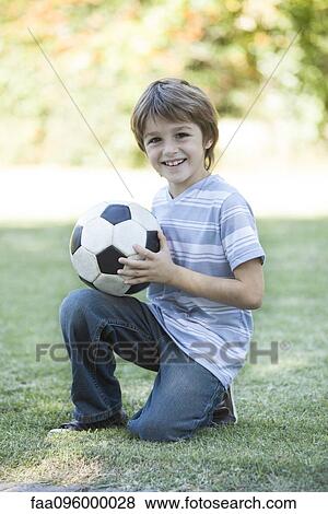 Stock Photo - Boy holding soccer ball, portrait. Fotosearch
