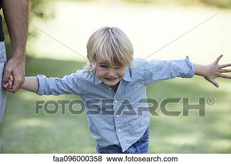 Stock Photo - Boy playing outdoors, holding father's hand. Fotosearch