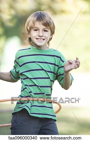 Stock Image - Boy playing with hula hoop in yard. Fotosearch