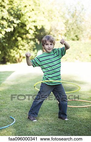 Stock Image - Boy playing with hula hoops in yard. Fotosearch