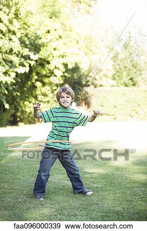 Boy playing with hula hoops in yard View Large Photo Image Stock Photo - Boy playing with hula hoops in yard. Fotosearch