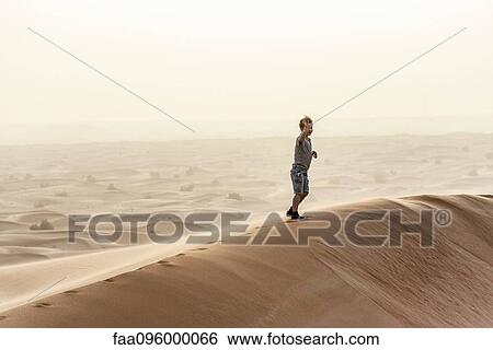 Boy walking on top of desert dune View Large Photo Image Stock Photograph - Boy walking on top of desert dune. Fotosearch