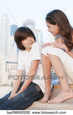 Stock Image - Brother and sister talking together outdoors. Fotosearch