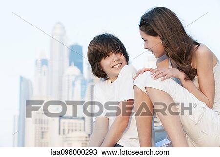 Stock Image - Brother and sister talking together outdoors. Fotosearch