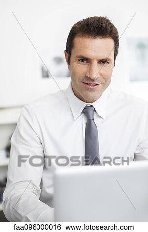 Businessman using laptop working in office View Large Photo Image Stock Photograph - Businessman using laptop working in office. Fotosearch