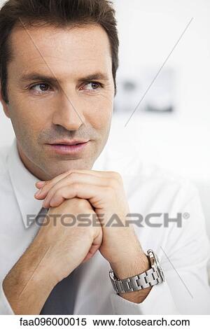 Businessman with hands clasped under chin, portrait View Large Photo Image Stock Photography - Businessman with hands clasped under chin, portrait. Fotosearch