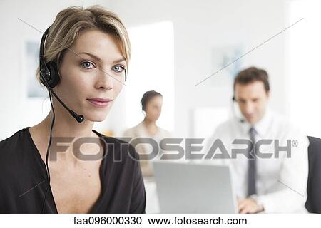 Stock Image - Businesswoman wearing headset working in office. Fotosearch