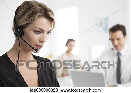 Stock Photo - Businesswoman wearing headset working in office. Fotosearch