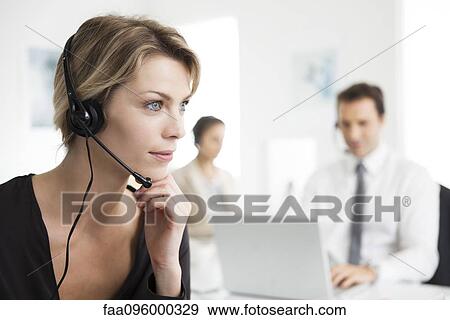 Businesswoman wearing headset working in office View Large Photo Image Stock Photo - Businesswoman wearing headset working in office. Fotosearch