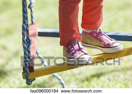 Picture - Child standing on swing, low section. Fotosearch
