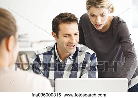 Stock Photography - Colleagues collaborating on work project. Fotosearch
