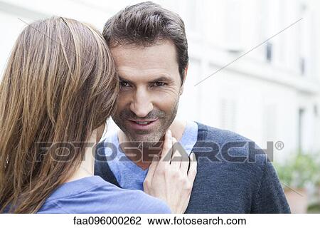 Stock Image - Couple embracing, man looking at camera. Fotosearch