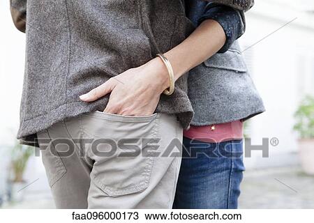 Couple embracing, woman placing hand in man's pant seat pocket View Large Photo Image Stock Image - Couple embracing, woman placing hand in man's pant seat pocket. Fotosearch