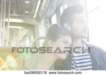 Stock Photograph - Couple riding train together, looking out window. Fotosearch