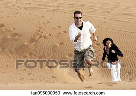 Couple running up desert dune View Large Photo Image Stock Photo - Couple running up desert dune. Fotosearch