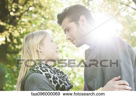 Couple standing together outdoors, looking into each other's eyes View Large Photo Image Stock Photo - Couple standing together outdoors, looking into each other's eyes. Fotosearch
