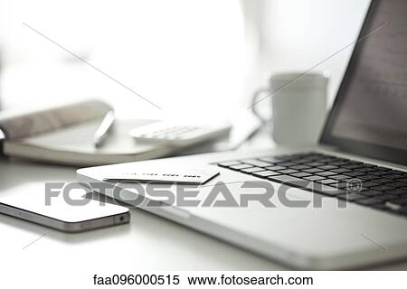 Stock Photography - Credit card resting on laptop computer in home office. Fotosearch
