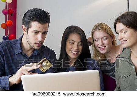 Friends gathered around laptop computer preparing to use credit card for online purchase View Large Photo Image Stock Photography - Friends gathered around laptop computer preparing to use credit card for online purchase. Fotosearch