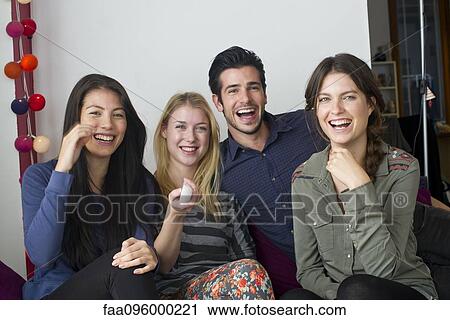 Stock Image - Friends watching movie at home together. Fotosearch