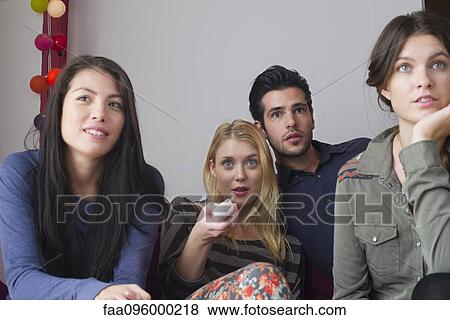Stock Photo - Friends watching movie at home together. Fotosearch