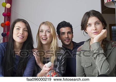 Stock Photo - Friends watching movie at home together. Fotosearch