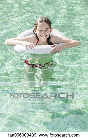 Stock Photo - Girl floating in swimming pool, portrait. Fotosearch