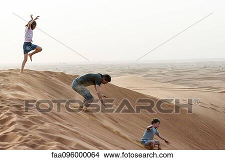 Picture - Girl jumping on desert dune. Fotosearch