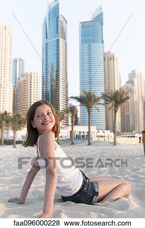 Girl sitting on beach, smiling over shoulder View Large Photo Image Stock Photo - Girl sitting on beach, smiling over shoulder. Fotosearch
