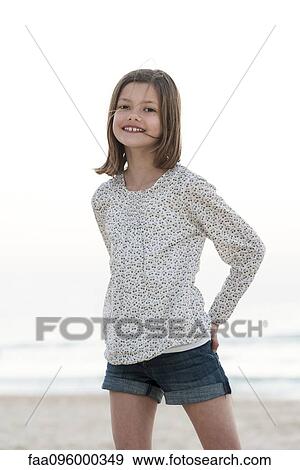 Stock Photo - Girl standing on beach, smiling, portrait. Fotosearch
