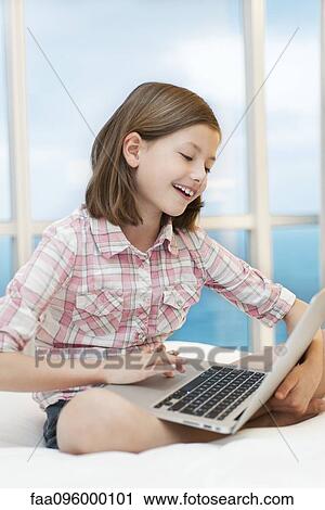 Stock Image - Girl using laptop computer, smiling. Fotosearch