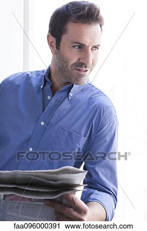 Stock Image - Man with newspaper looking out window. Fotosearch