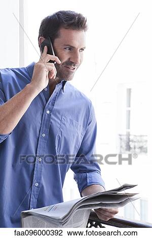 Man with newspaper making phone call View Large Photo Image Stock Image - Man with newspaper making phone call. Fotosearch