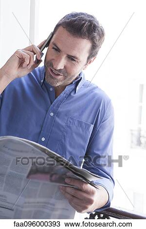 Stock Image - Man with newspaper making phone call. Fotosearch