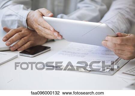 Stock Image - Men using digital tablet, cropped. Fotosearch
