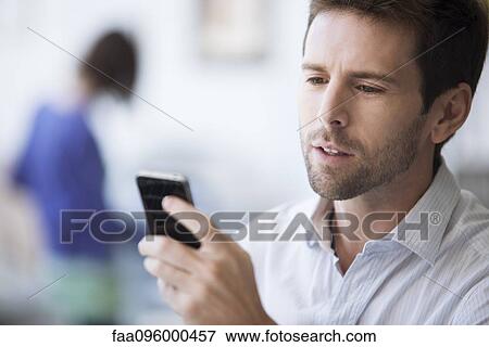 Stock Photo - Mid-adult man checking cell phone. Fotosearch