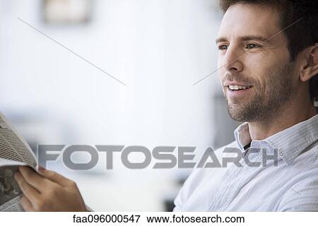 Mid-adult man reading newspaper View Large Photo Image Stock Photo - Mid-adult man reading newspaper. Fotosearch