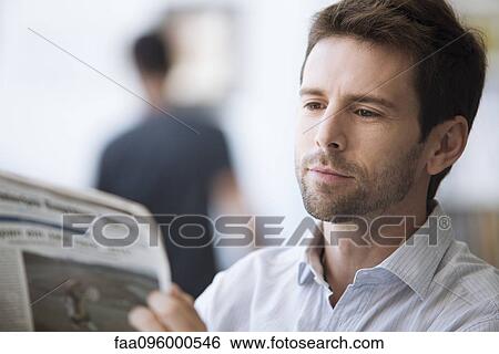 Stock Photograph - Mid-adult man reading newspaper, portrait. Fotosearch