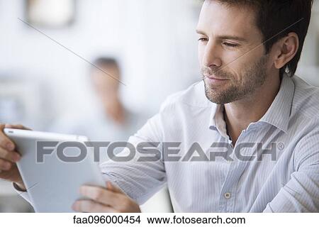 Picture - Mid-adult man using digital tablet. Fotosearch