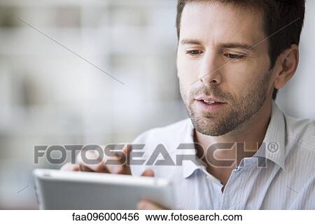 Mid-adult man using digital tablet View Large Photo Image Stock Photograph - Mid-adult man using digital tablet. Fotosearch