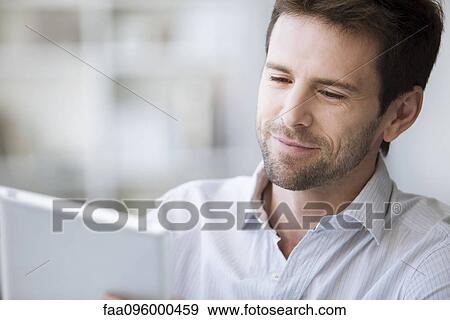 Stock Photo - Mid-adult man using e-reader. Fotosearch