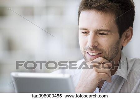 Mid-adult man using e-reader View Large Photo Image Stock Photography - Mid-adult man using e-reader. Fotosearch