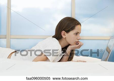 Preteen girl lying on stomach using laptop computer View Large Photo Image Stock Photography - Preteen girl lying on stomach using laptop computer. Fotosearch