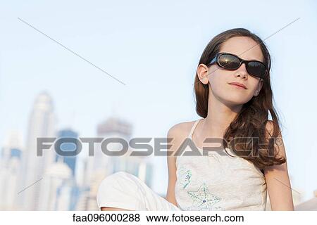 Stock Photo - Preteen girl relaxing outdoors, wearing sunglasses. Fotosearch