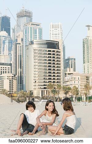 Siblings sitting together on beach, Dubai, United Arab Emirates View Large Photo Image Stock Photo - Siblings sitting together on beach, Dubai, United Arab Emirates. Fotosearch