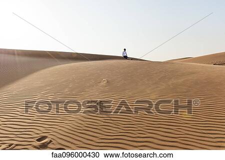 Teenage boy sitting alone on desert dune View Large Photo Image Stock Image - Teenage boy sitting alone on desert dune. Fotosearch