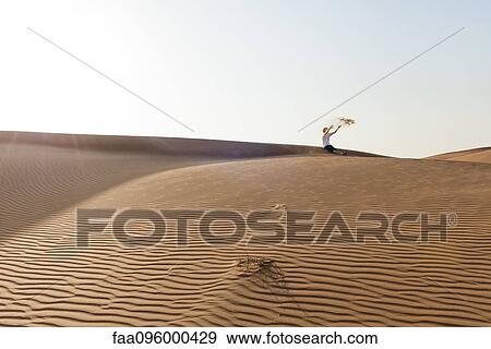 Teenage boy sitting on desert dune, throwing sand in air View Large Photo Image Stock Photo - Teenage boy sitting on desert dune, throwing sand in air. Fotosearch